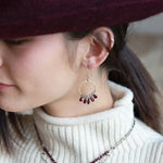 Smooth garnet drops line the bottom of a brass hammered hoop earring with the inside lined in faceted labradorite gemstones