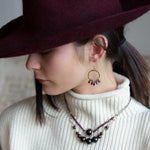 Smooth garnet drops line the bottom of a brass hammered hoop earring with the inside lined in faceted labradorite gemstones