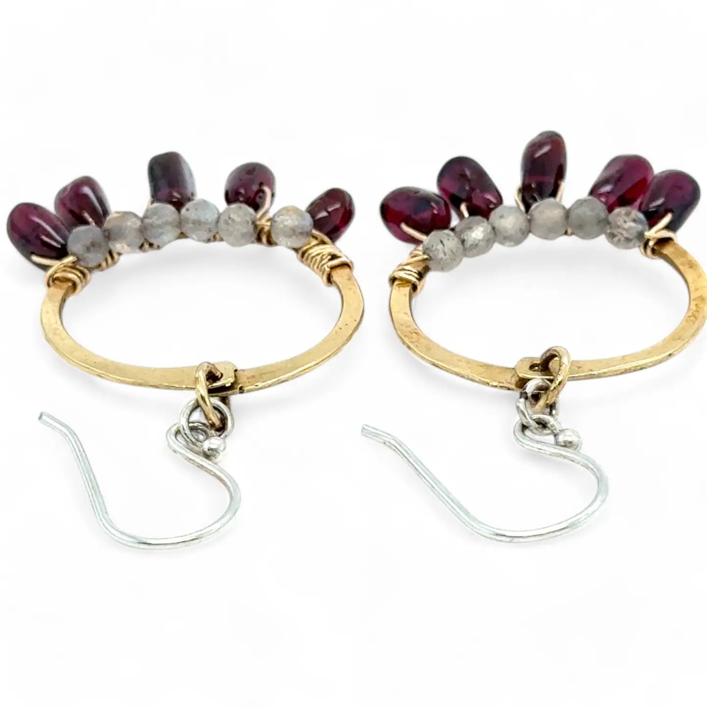 Smooth garnet drops line the bottom of a brass hammered hoop earring with the inside lined in faceted labradorite gemstones