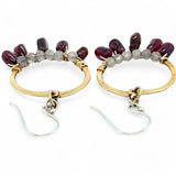 Smooth garnet drops line the bottom of a brass hammered hoop earring with the inside lined in faceted labradorite gemstones