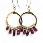 Smooth garnet drops line the bottom of a brass hammered hoop earring with the inside lined in faceted labradorite gemstones