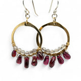 Smooth garnet drops line the bottom of a brass hammered hoop earring with the inside lined in faceted labradorite gemstones
