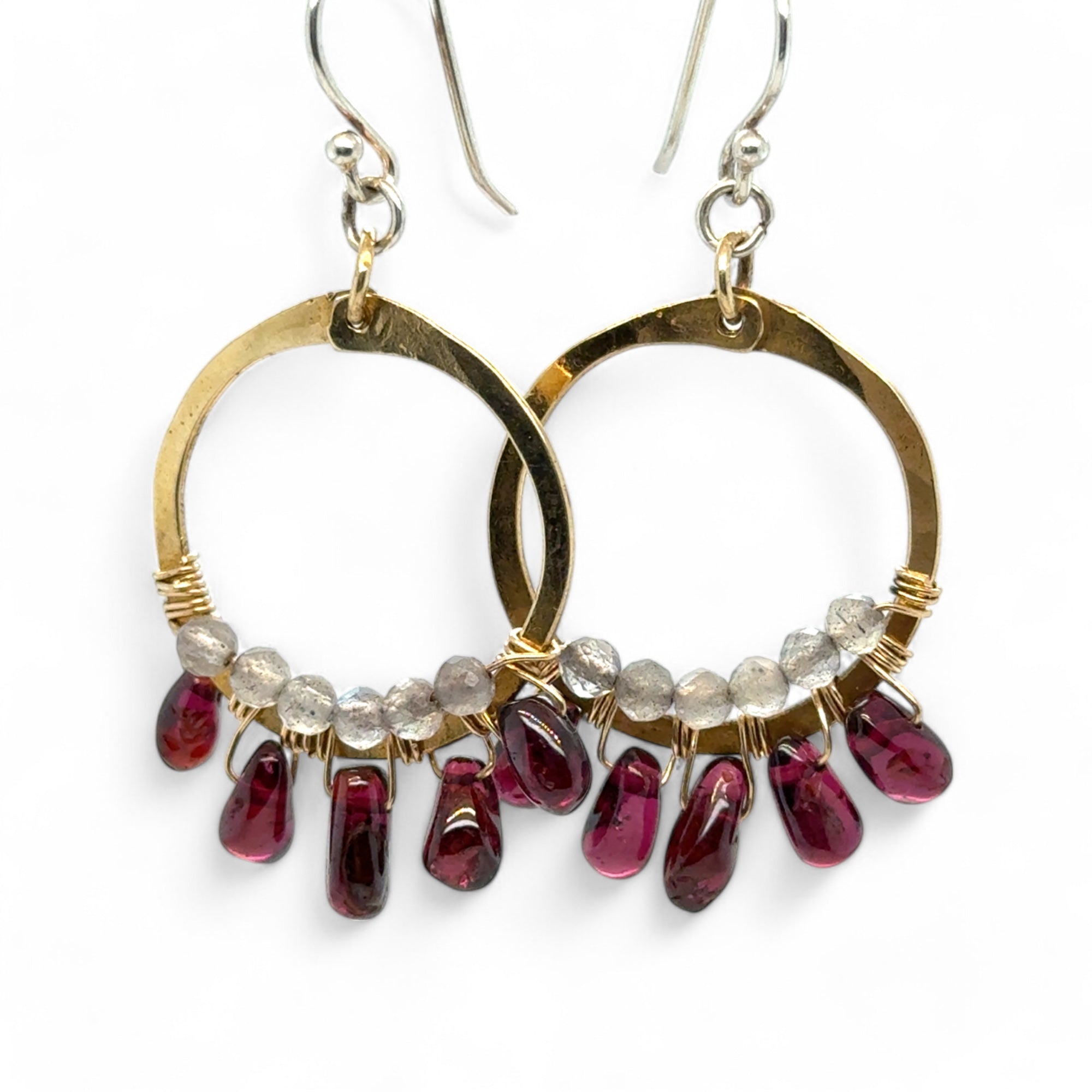 Smooth garnet drops line the bottom of a brass hammered hoop earring with the inside lined in faceted labradorite gemstones