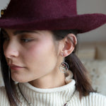 A pair of handmade petite double hoop earrings with red tiger's eye and garnet gemstones, set in hammered brass arches with sterling silver French hooks.