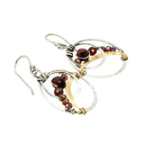 A pair of handmade petite double hoop earrings with red tiger's eye and garnet gemstones, set in hammered brass arches with sterling silver French hooks.
