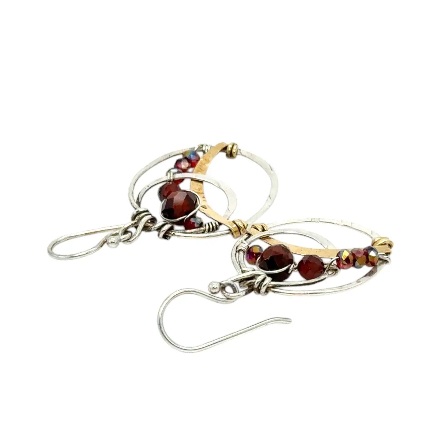 A pair of handmade petite double hoop earrings with red tiger's eye and garnet gemstones, set in hammered brass arches with sterling silver French hooks.