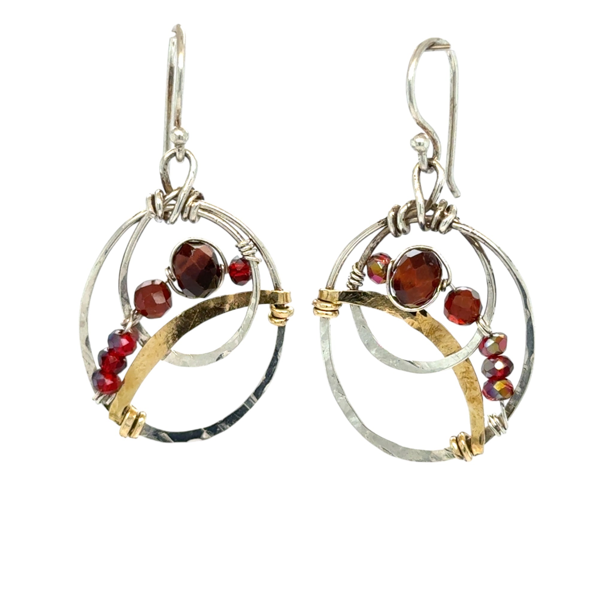 A pair of handmade petite double hoop earrings with red tiger's eye and garnet gemstones, set in hammered brass arches with sterling silver French hooks.