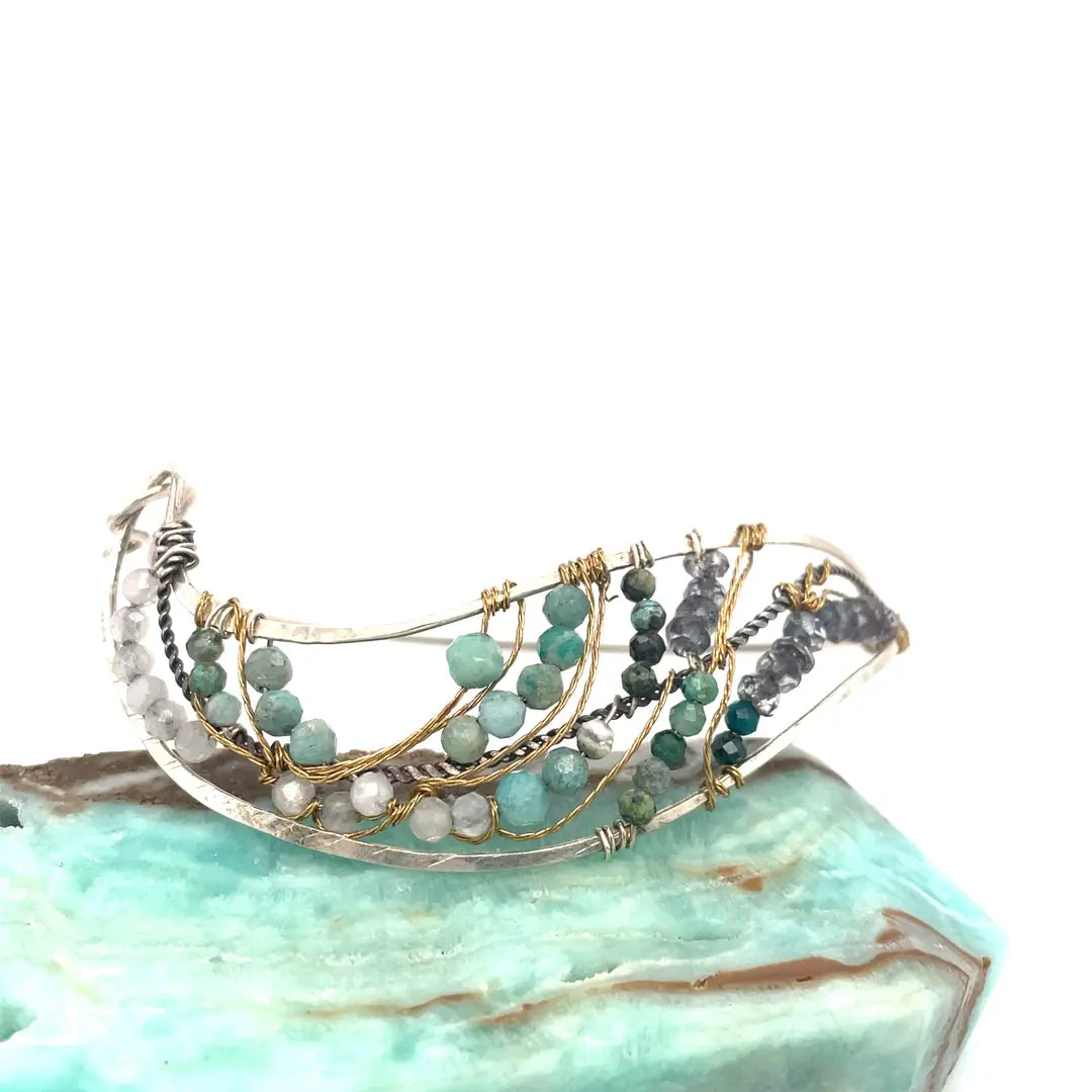 Amazonite, chrysocolla, blue quartz, and moonstone gemstones held within a handmade sterling silver wave shaped bracelet with oxidized twist, gold filled, and brass wire accents