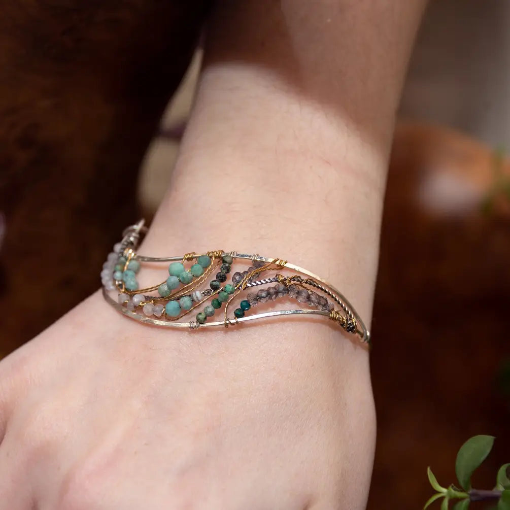 Amazonite, chrysocolla, blue quartz, and moonstone gemstones held within a handmade sterling silver wave shaped bracelet with oxidized twist, gold filled, and brass wire accents