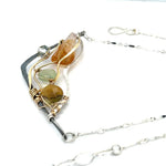 An oxidized sterling silver wedge pendant with waves of hammered sterling silver and brass wires, mixed with citrine, jade, crystal, and yellow opal gemstones to form this gemstone wedge necklace