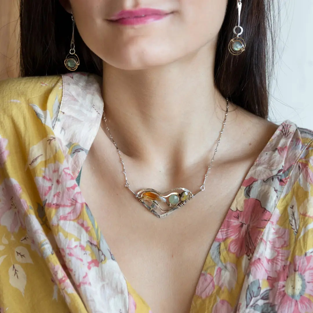 An oxidized sterling silver wedge pendant with waves of hammered sterling silver and brass wires, mixed with citrine, jade, crystal, and yellow opal gemstones to form this gemstone wedge necklace