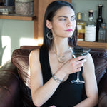 A collection of labradorite, purple blue fresh water pearl, green crystal, and quartz gemstones on a dandelion stamped oxidized sterling silver wide cuff bracelet