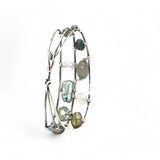 A collection of labradorite, purple blue fresh water pearl, green crystal, and quartz gemstones on a dandelion stamped oxidized sterling silver wide cuff bracelet