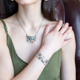 A collection of labradorite, purple blue fresh water pearl, green crystal, and quartz gemstones on a dandelion stamped oxidized sterling silver wide cuff bracelet