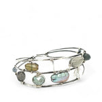 A collection of labradorite, purple blue fresh water pearl, green crystal, and quartz gemstones on a dandelion stamped oxidized sterling silver wide cuff bracelet