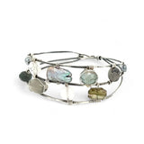 A collection of labradorite, purple blue fresh water pearl, green crystal, and quartz gemstones on a dandelion stamped oxidized sterling silver wide cuff bracelet