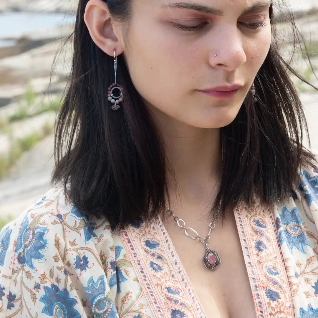 Darkened sterling silver ring surrounded by pink tourmaline and opal gemstones with a herkimer diamond dangle, attached to a darkened sterling silver twisted bar top earring