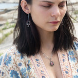 Darkened sterling silver ring surrounded by pink tourmaline and opal gemstones with a herkimer diamond dangle, attached to a darkened sterling silver twisted bar top earring