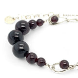Smooth garnet sphere gemstones are suspended between handmade sterling silver hammered teardrops on sterling rolo chain necklace