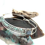 A sterling silver cuff bracelet featuring labradorite luster faceted gemstone cubes, and lines of mint crystal and pyrite, displayed on a sterling silver cuff bracelet