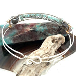 A sterling silver cuff bracelet featuring labradorite luster faceted gemstone cubes, and lines of mint crystal and pyrite, displayed on a sterling silver cuff bracelet