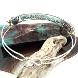 A sterling silver cuff bracelet featuring labradorite luster faceted gemstone cubes, and lines of mint crystal and pyrite, displayed on a sterling silver cuff bracelet