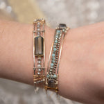 A sterling silver cuff bracelet featuring labradorite luster faceted gemstone cubes, and lines of mint crystal and pyrite, displayed on a sterling silver cuff bracelet