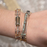 A sterling silver cuff bracelet featuring labradorite luster faceted gemstone cubes, and lines of mint crystal and pyrite, displayed on a sterling silver cuff bracelet