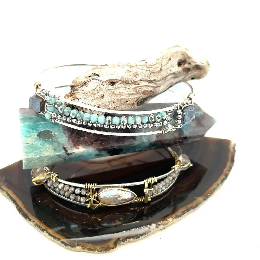 A sterling silver cuff bracelet featuring labradorite luster faceted gemstone cubes, and lines of mint crystal and pyrite, displayed on a sterling silver cuff bracelet