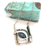 London blue quartz, pyrite, bloodstone, and blue tourmaline gemstones sit within a brass box pendant with sterling silver and gold filled wire accents on a sterling silver box chain
