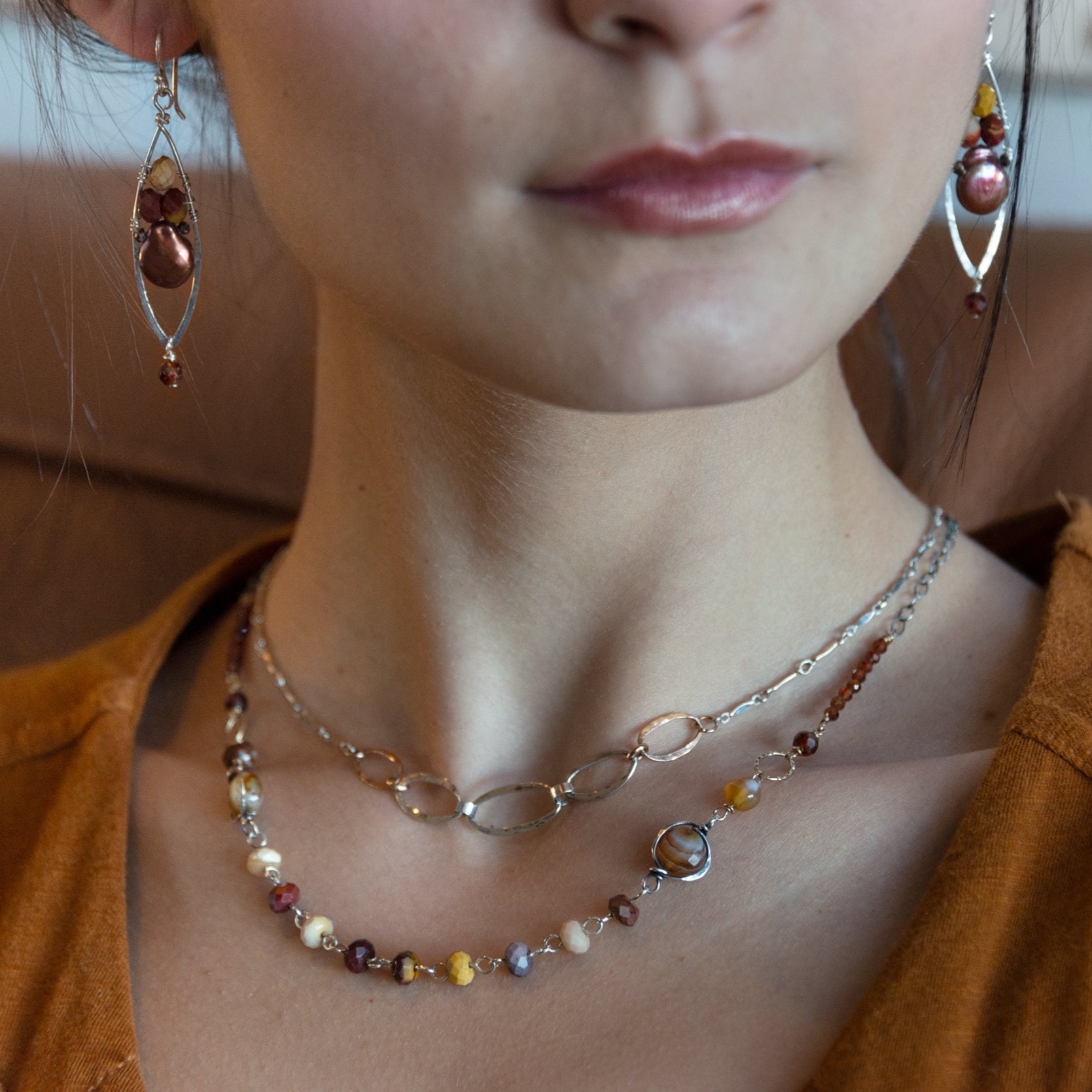 Mookaite, striped agate, and hessonite garnet gemstones are linked together on sterling silver wire and chain to form a beaded chain necklace