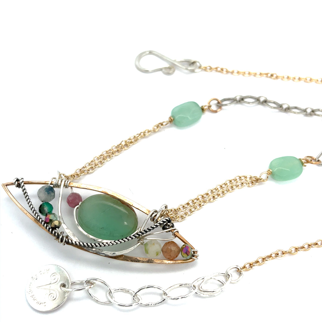 An eye shaped hammered bronze pendant with chrysoprase, tourmaline, crystal, and jade gemstones on delicate double gold filled chain attached to jade faceted gemstones on textured oxidized sterling silver chain necklace