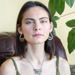 Flashy half moon shaped labradorite gemstones sitting inside a layer of sterling silver wire inside a large hammered brass hook earring with built in earring hooks to wear like a post earring