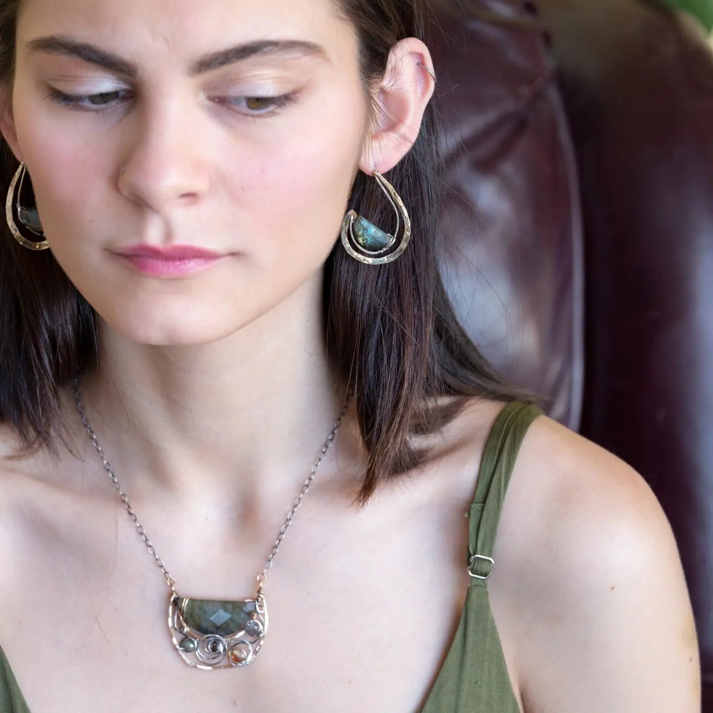 Flashy half moon shaped labradorite gemstones sitting inside a layer of sterling silver wire inside a large hammered brass hook earring with built in earring hooks to wear like a post earring