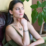 Flashy half moon shaped labradorite gemstones sitting inside a layer of sterling silver wire inside a large hammered brass hook earring with built in earring hooks to wear like a post earring