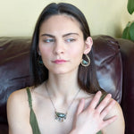 Flashy half moon shaped labradorite gemstones sitting inside a layer of sterling silver wire inside a large hammered brass hook earring with built in earring hooks to wear like a post earring