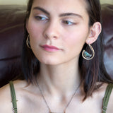 Flashy half moon shaped labradorite gemstones sitting inside a layer of sterling silver wire inside a large hammered brass hook earring with built in earring hooks to wear like a post earring