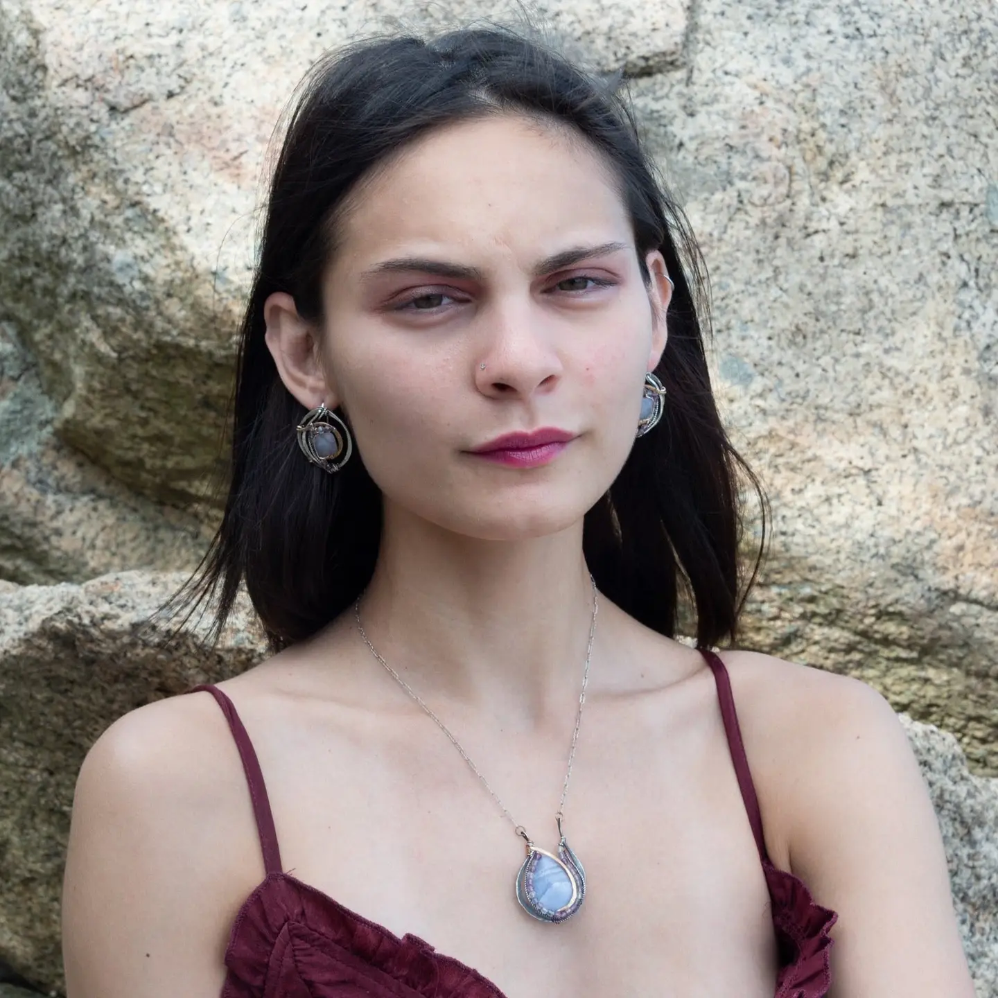 A blue lace agate drop pendant necklace with faceted natural fluorite gemstones, set in hammered bronze and twisted oxidized sterling silver, on a darkened floral stamped sterling silver pendant