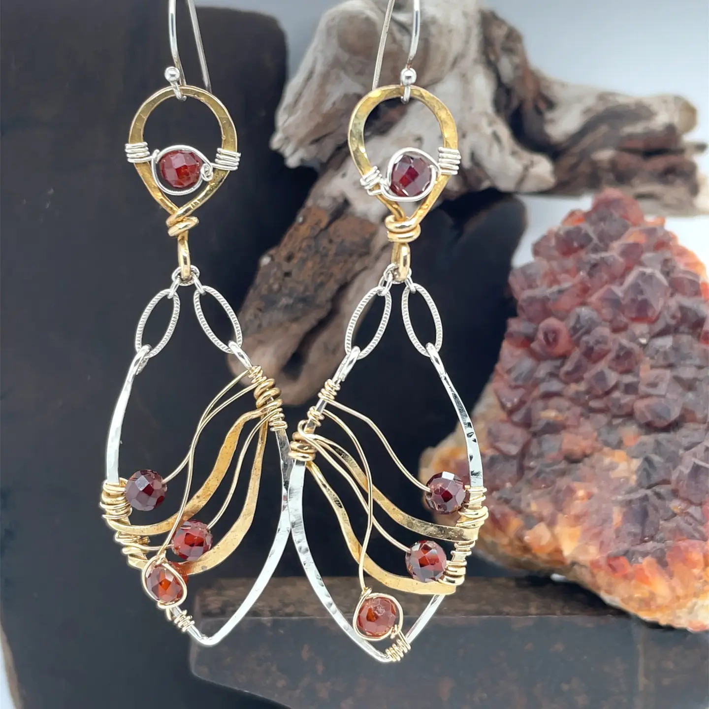 A pair of gold-filled, hammered brass and sterling silver earrings with faceted hessonite garnet gemstones, featuring sterling silver french hooks.