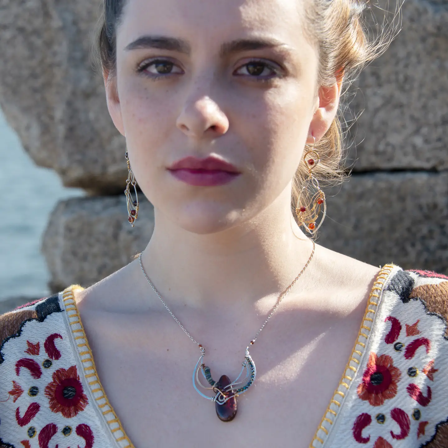 A pair of gold-filled, hammered brass and sterling silver earrings with faceted hessonite garnet gemstones, featuring sterling silver french hooks.