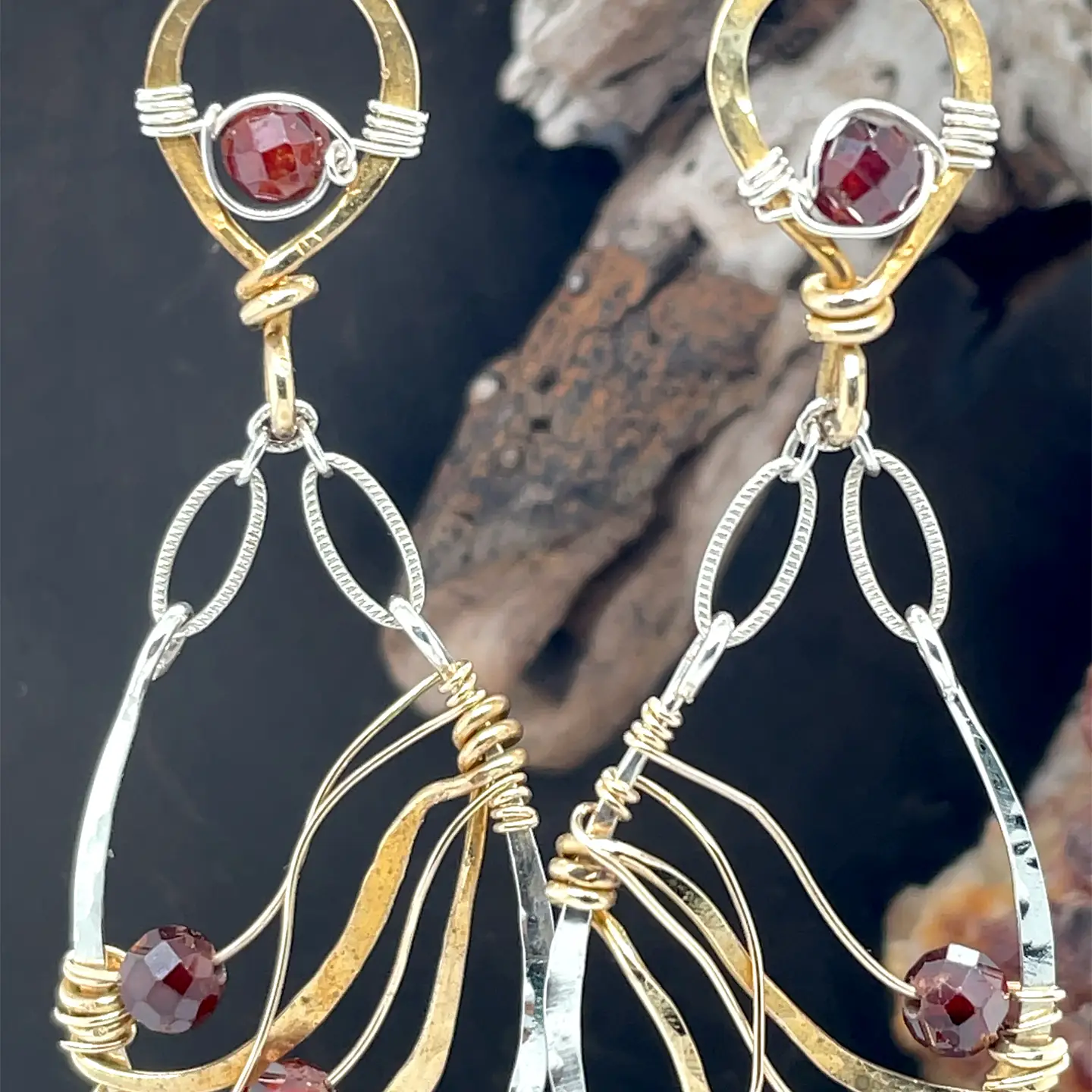 A pair of gold-filled, hammered brass and sterling silver earrings with faceted hessonite garnet gemstones, featuring sterling silver french hooks.
