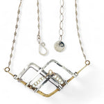 Brass and oxidized stamped sterling silver points to create a mountain scape adorned with fresh water pearl wrapped in gold filled wire on a dainty sterling silver chain necklace