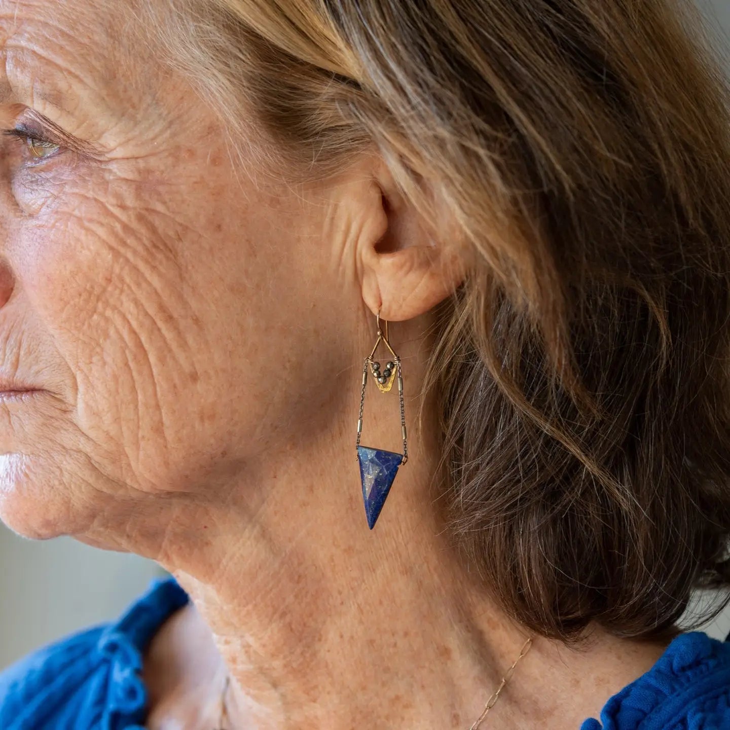 Faceted lapis triangles hang from oxidized and gold dot chain hanging from brass mini diamonds lined with pyrite earrings
