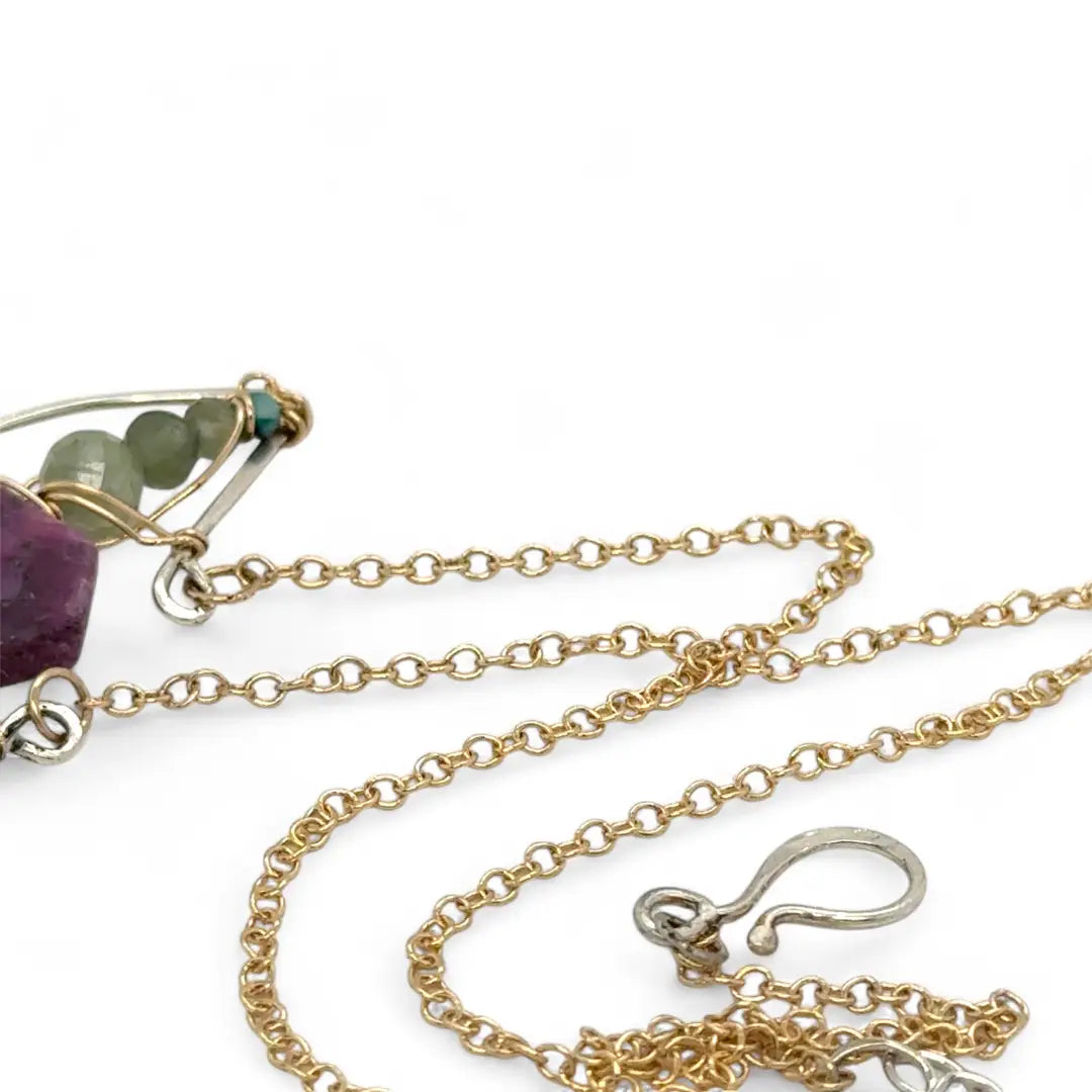 Pink tourmaline hexagon slice surrounded by green kyanite gemstones inside a hammered sterling silver boat shaped pendant, wrapped in gold fill wire with gold filled delicate chain necklace