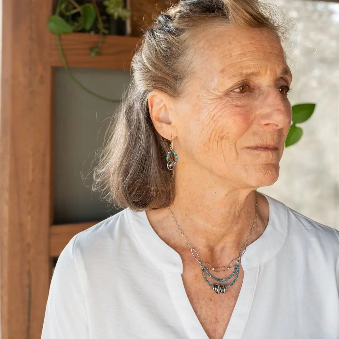 A sterling silver oxidized knot is set on layers of bright blue apatite gemstones with silver crystal cube accents, oxidized sterling diamond cut links and a dainty sterling chain necklace 