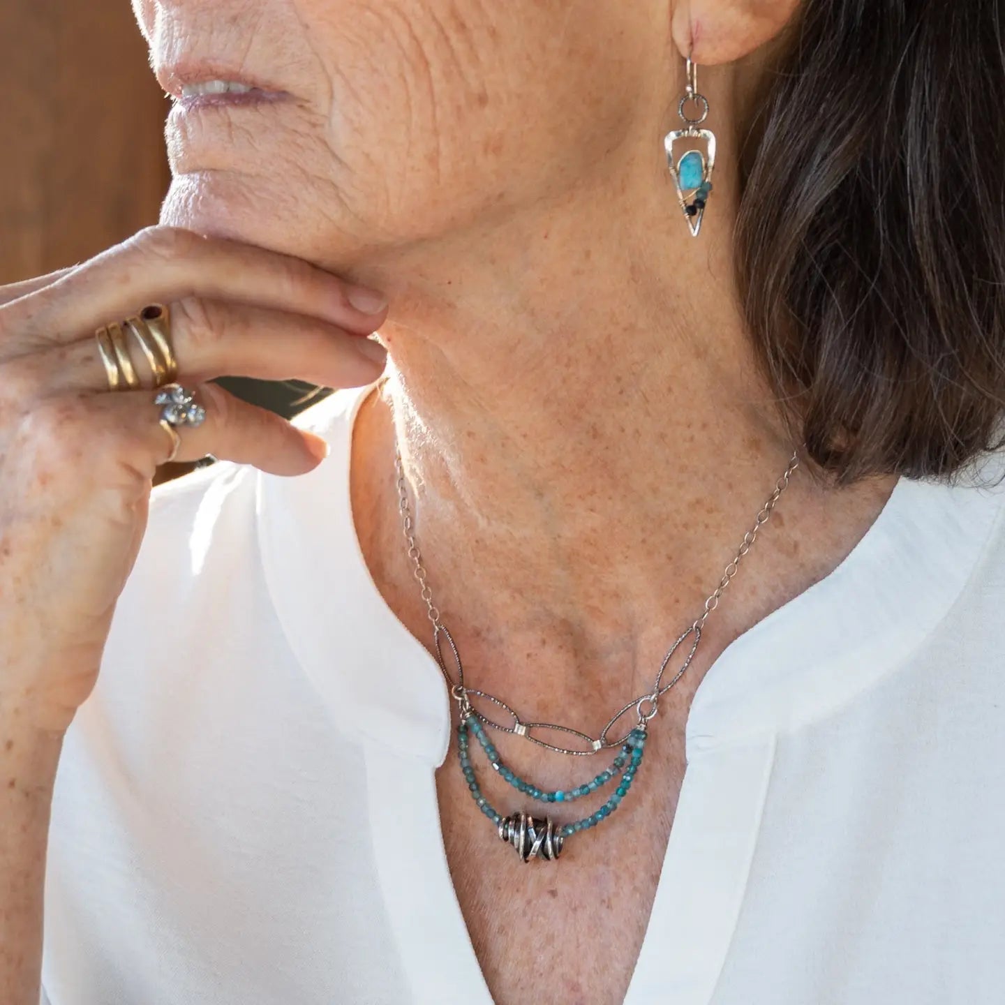 A sterling silver oxidized knot is set on layers of bright blue apatite gemstones with silver crystal cube accents, oxidized sterling diamond cut links and a dainty sterling chain necklace 