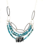 A sterling silver oxidized knot is set on layers of bright blue apatite gemstones with silver crystal cube accents, oxidized sterling diamond cut links and a dainty sterling chain necklace 