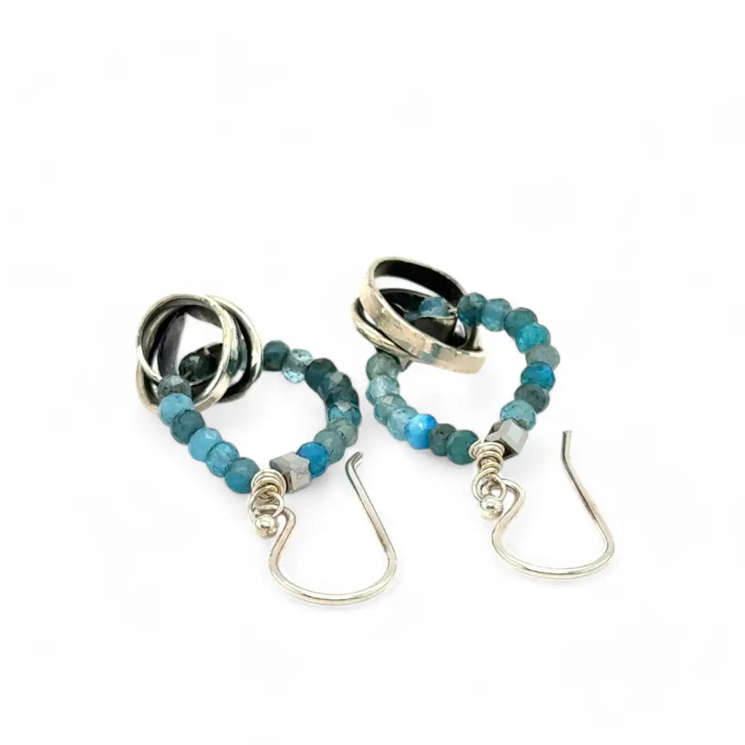 Faceted apatite gemstones form a ring that holds onto and oxidized sterling silver hand formed knot earring