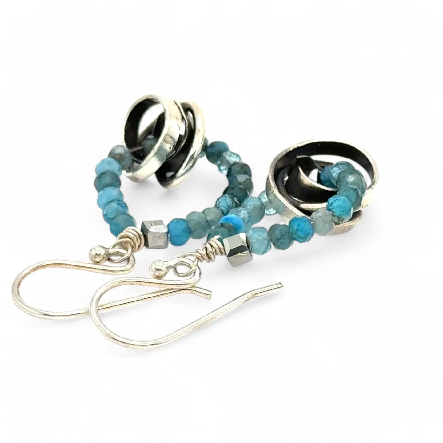 Faceted apatite gemstones form a ring that holds onto and oxidized sterling silver hand formed knot earring