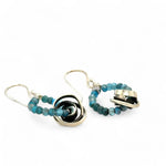 Faceted apatite gemstones form a ring that holds onto and oxidized sterling silver hand formed knot earring